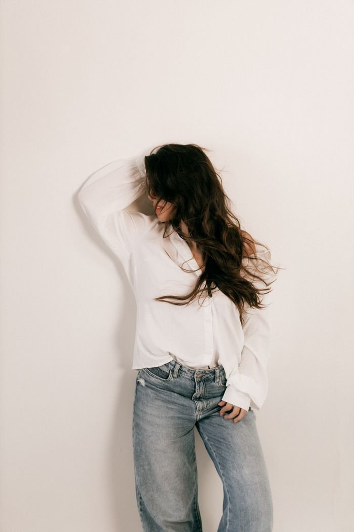 Stylish woman posing against a plain background, embracing a relaxed, casual fashion style.
