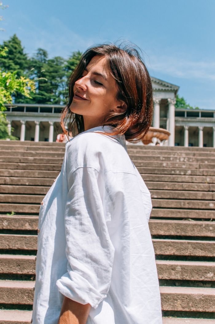 Side profile of a happy woman standing on stairs under a bright blue summer sky.